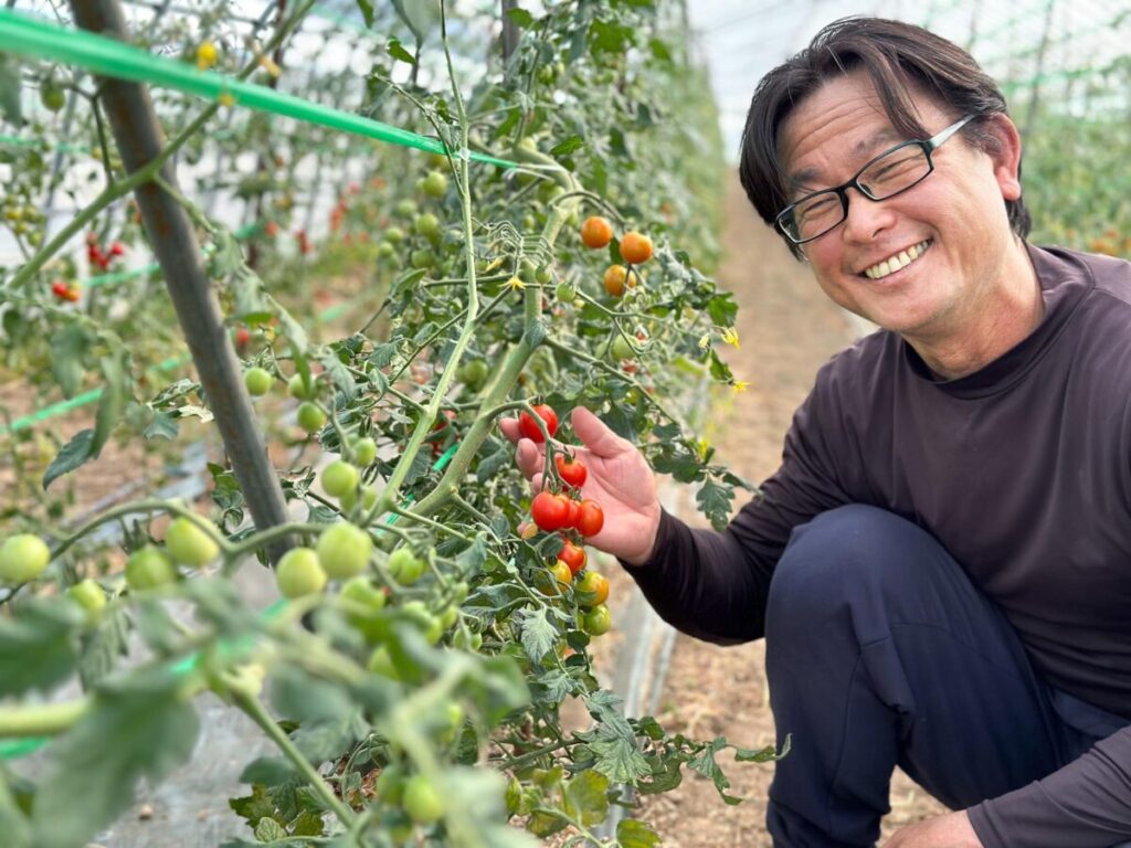 栽培中のミニトマトを手に笑顔の山本さん