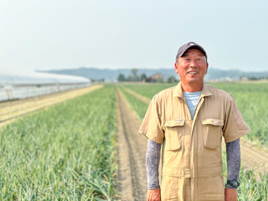 玉葱畑を背景に佇む武田さん