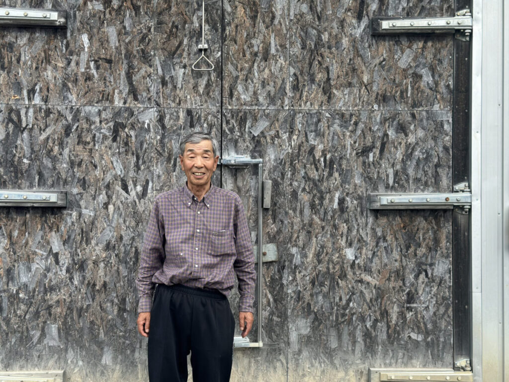 原谷農園の人参倉庫の前に立つ原谷さん